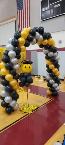 goldand+black+balloon+arch+with+a+smiley+face+balloon+in+a+gymnasium-1920w